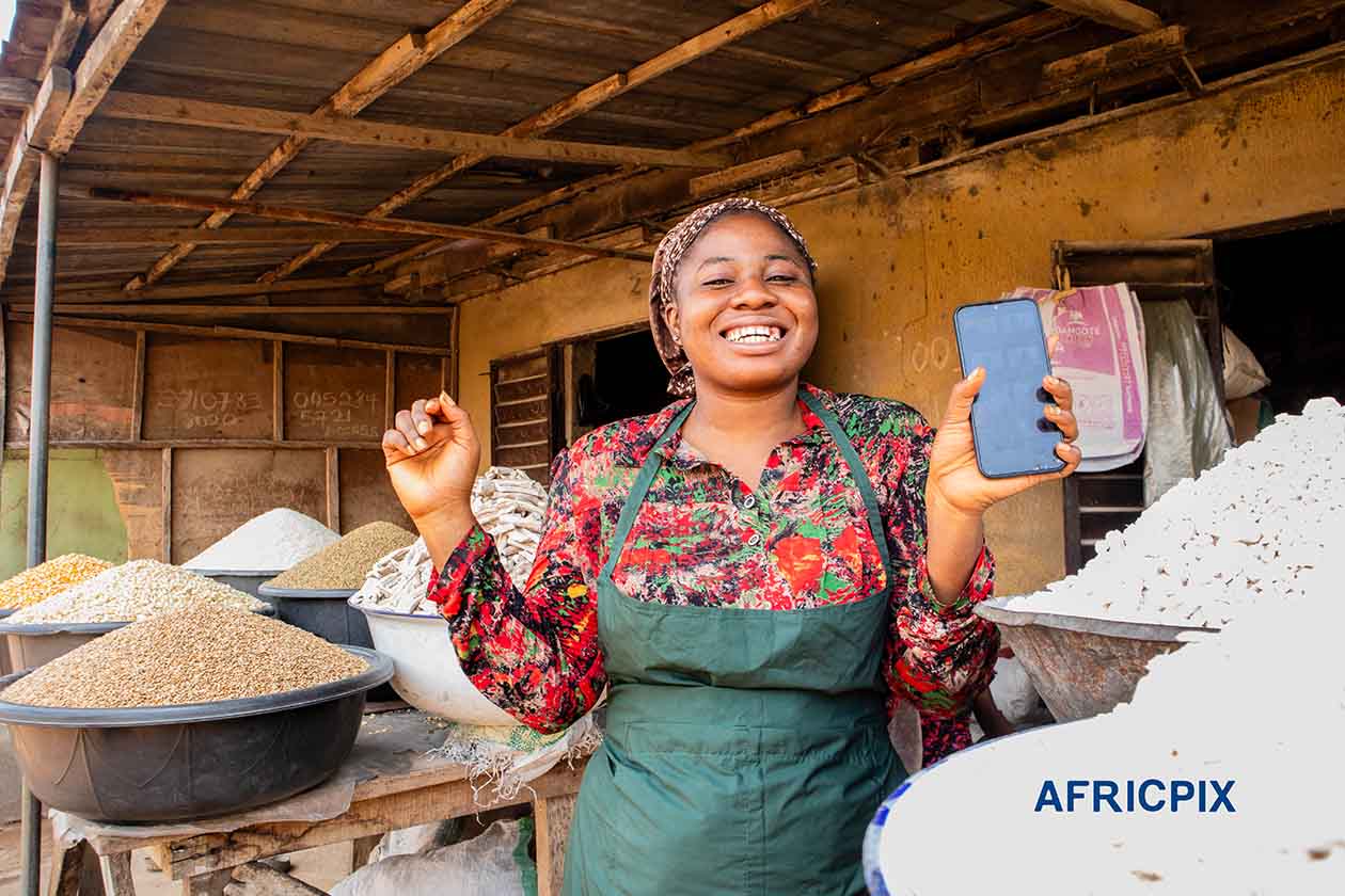 Joyful African Woman Holding POS Machine with Both Hands Raised in Celebration